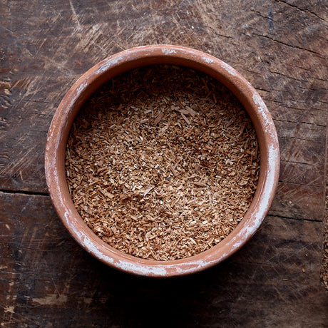 Top view of a mixture of small and large particles of Apple smoking wood dust in a flat round bowl.