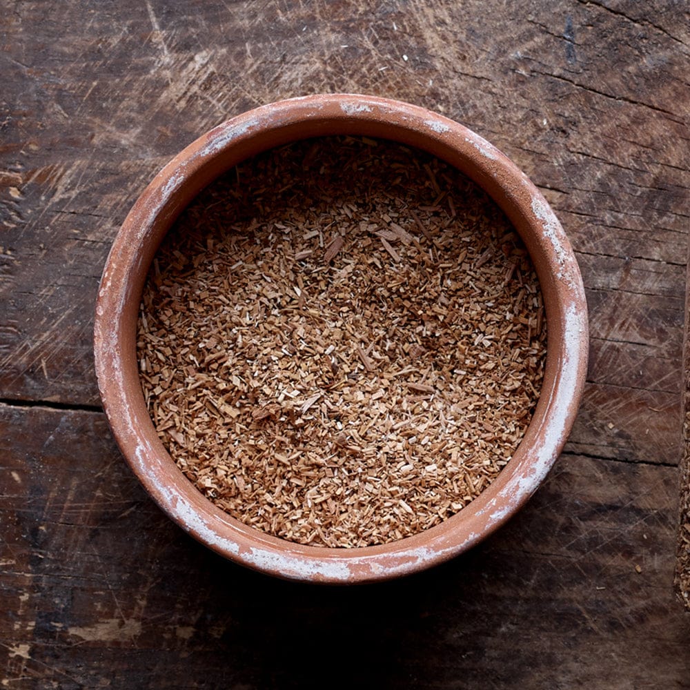 Top view of a mixture of small and large particles of Apple smoking wood dust in a flat round bowl.
