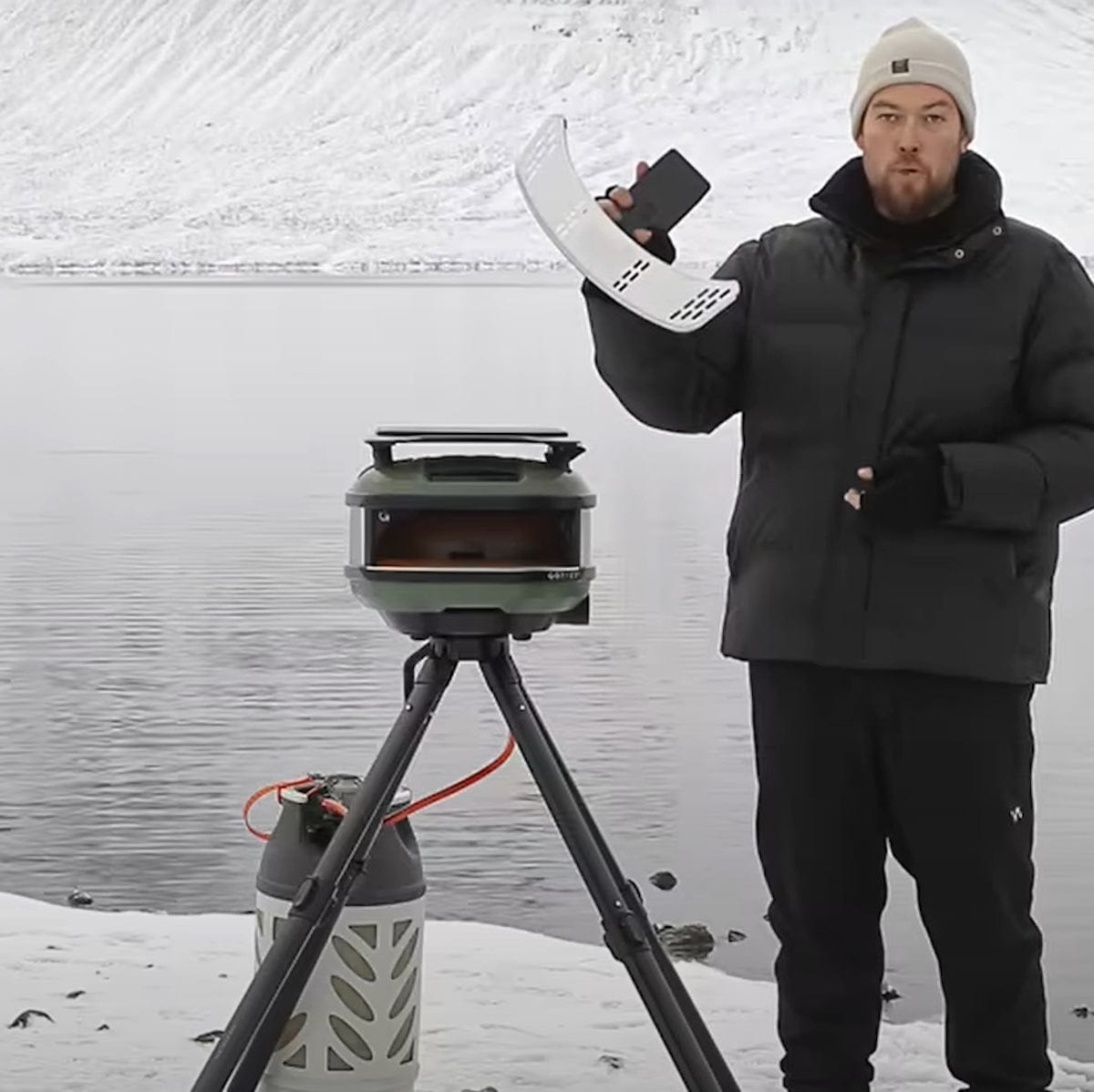Person demonstrating a Tread Mantel and pizza oven setup in a snowy outdoor location.