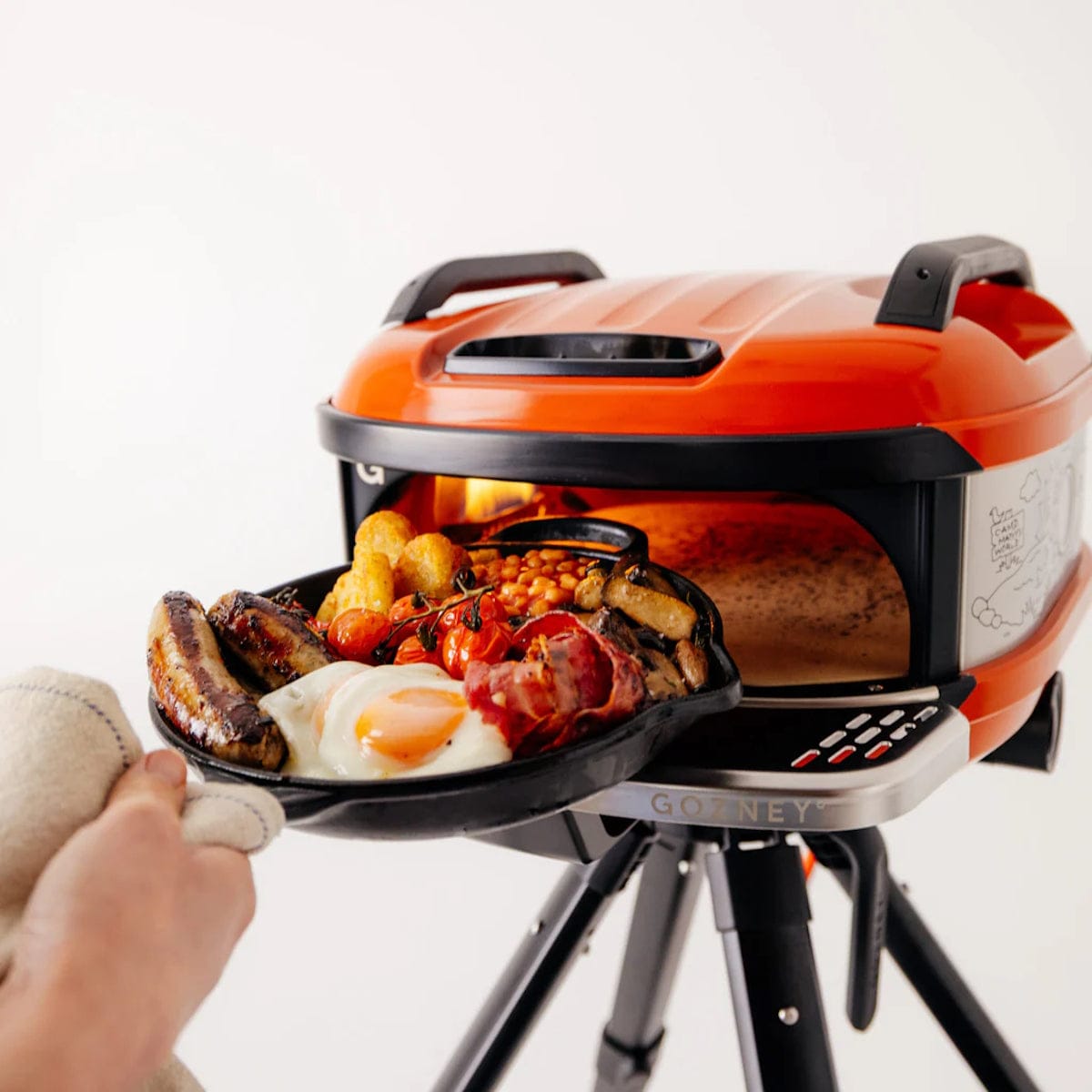 Gozney x Matty Matheson Portable Pizza Oven man holding iron pan with food