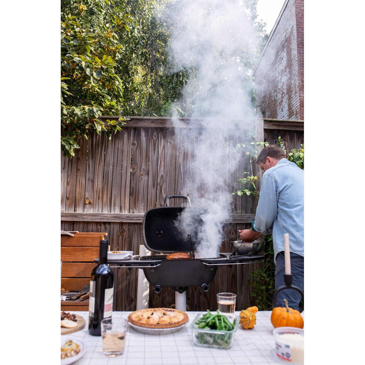 man smoking food on PK360 Aluminium Charcoal Grill & Smoker outside