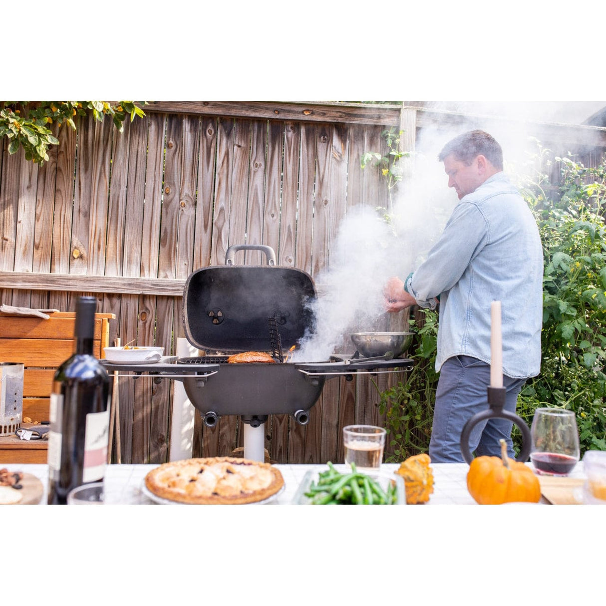 man preparing meal on PK360 Aluminium Charcoal Grill & Smoker outside