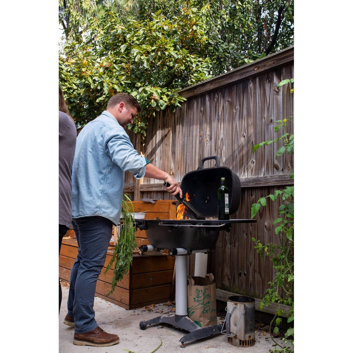 man grilling food on PK360 Aluminium Charcoal Grill & Smoker in backyard
