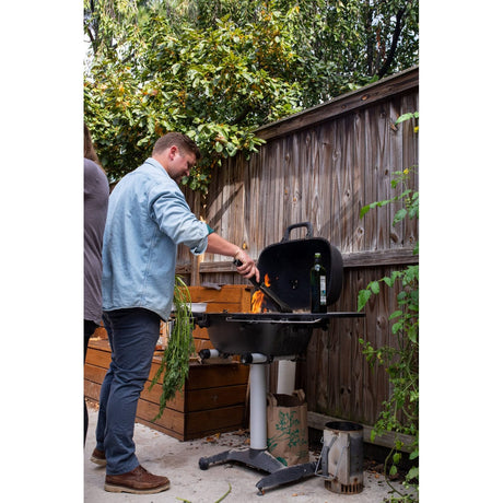 man grilling food on PK360 Aluminium Charcoal Grill & Smoker in backyard