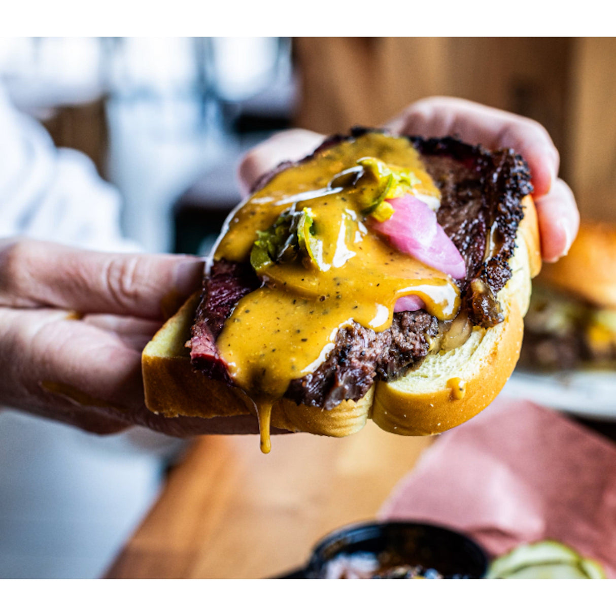 LeRoy & Lewis Mustard BBQ Sauce hands holding sandwich