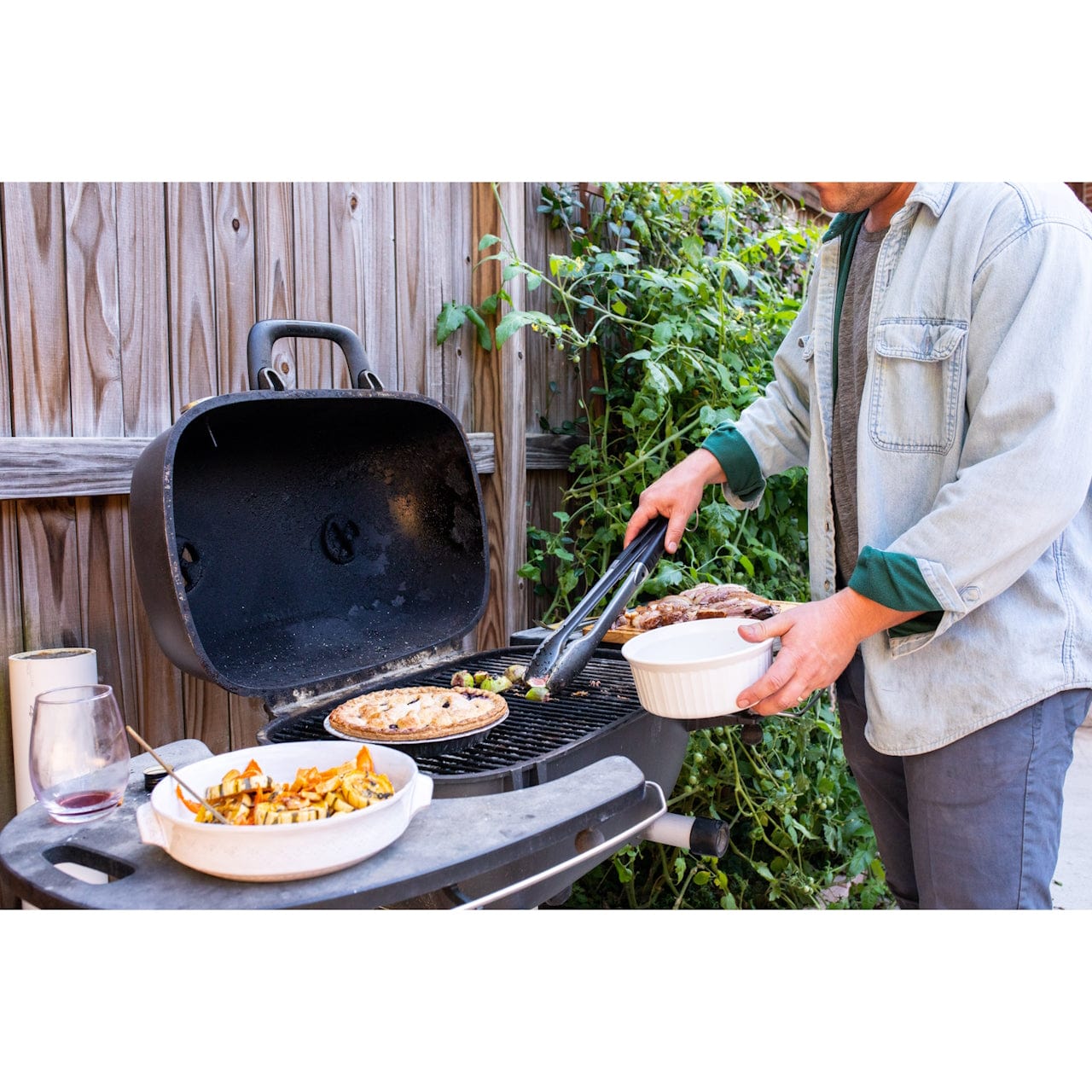 man grilling food on PK360 Aluminium Charcoal Grill & Smoker in backyard
