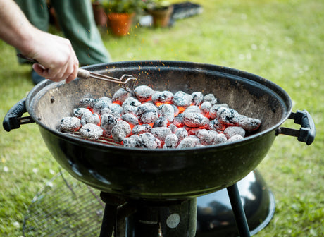 Hot charcoal briquettes glowing inside kettle BBQ grill