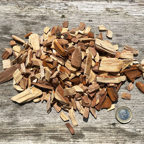 Close-up image of an ample amount of Plum Wood Smoking Chips and a coin penny to compare with the chip's size