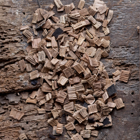 Close-up image of an ample amount of Whiskey Barrel Smoking Chips laid on a an old wooden board
