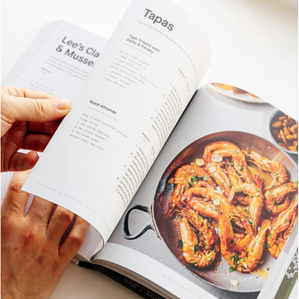 hands turning pages of Gozney Pizza Cookbook Volume 01