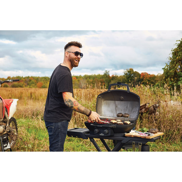 a man smiling and grilling food on Napoleon Phantom TravelQ portable