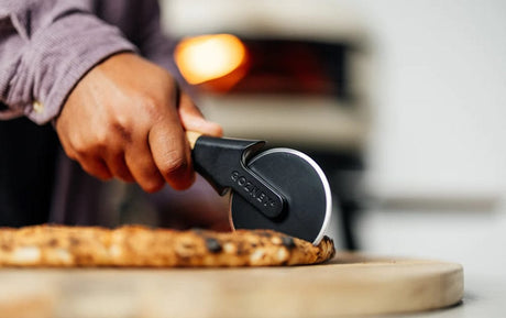 cutting pizza with Gozney Pizza Cutter