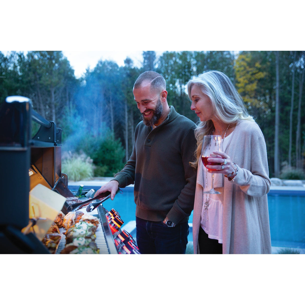 Napoleon Prestige PRO 825 RSBI man and woman grilling at dusk