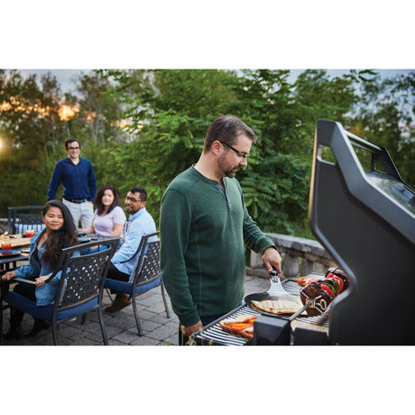 a man grilling food on Napoleon Rogue SE 625 RSIB and people in the background looking