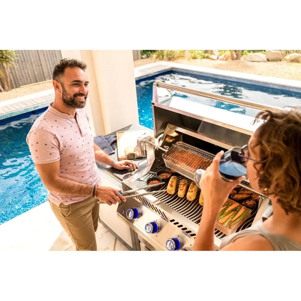 people grilling food on Napoleon Oasis 105 Outdoor Kitchen next to the swimming pool