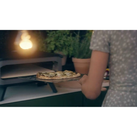 placing pizza into the oven with Cozze Large Pizza Paddle