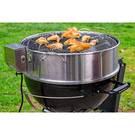 Close-up view of a working Slow 'N Sear® Kettle Ring Rotisserie Kit placed on top of a kettle grill with grate on top while grilling pieces of meat.