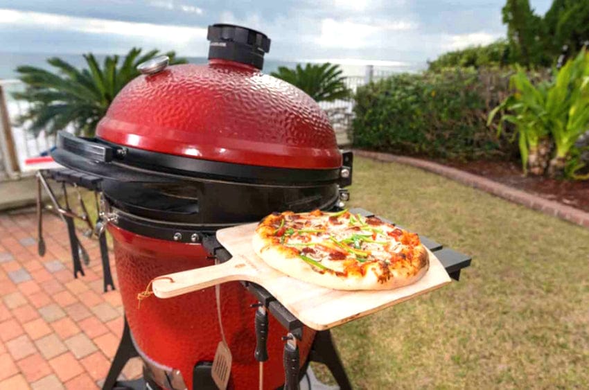 A pizza prep for cooking on a kamado joe pizza peel placed on top of a KJ grill shelf