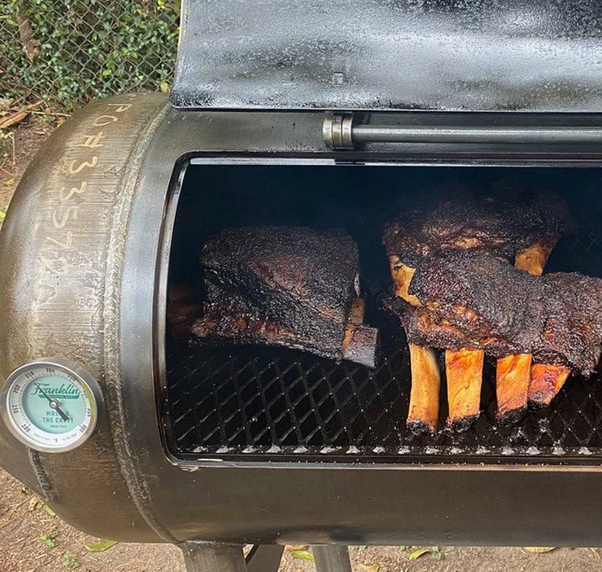 Grilled ribs on a Franklin Pit's cook chamber shown with lid open