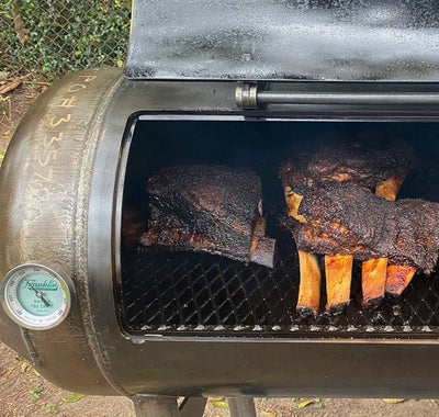 Grilled ribs on a Franklin Pit's cook chamber shown with lid open
